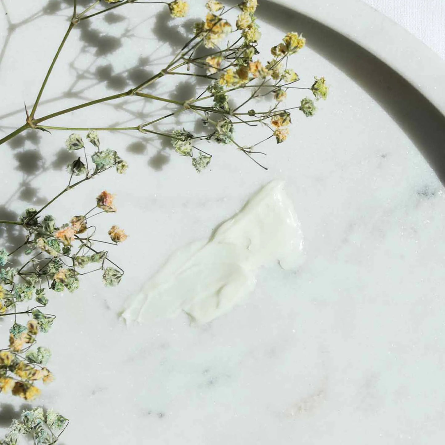 O creme foi espalhado numa mesa e um ramo de flores está por cima.