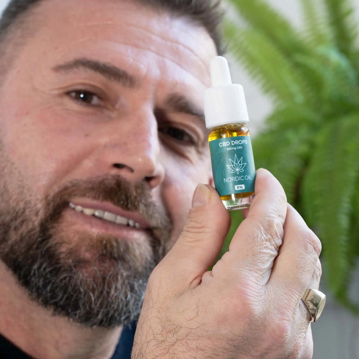 Um homem segura o óleo CBD para a câmara