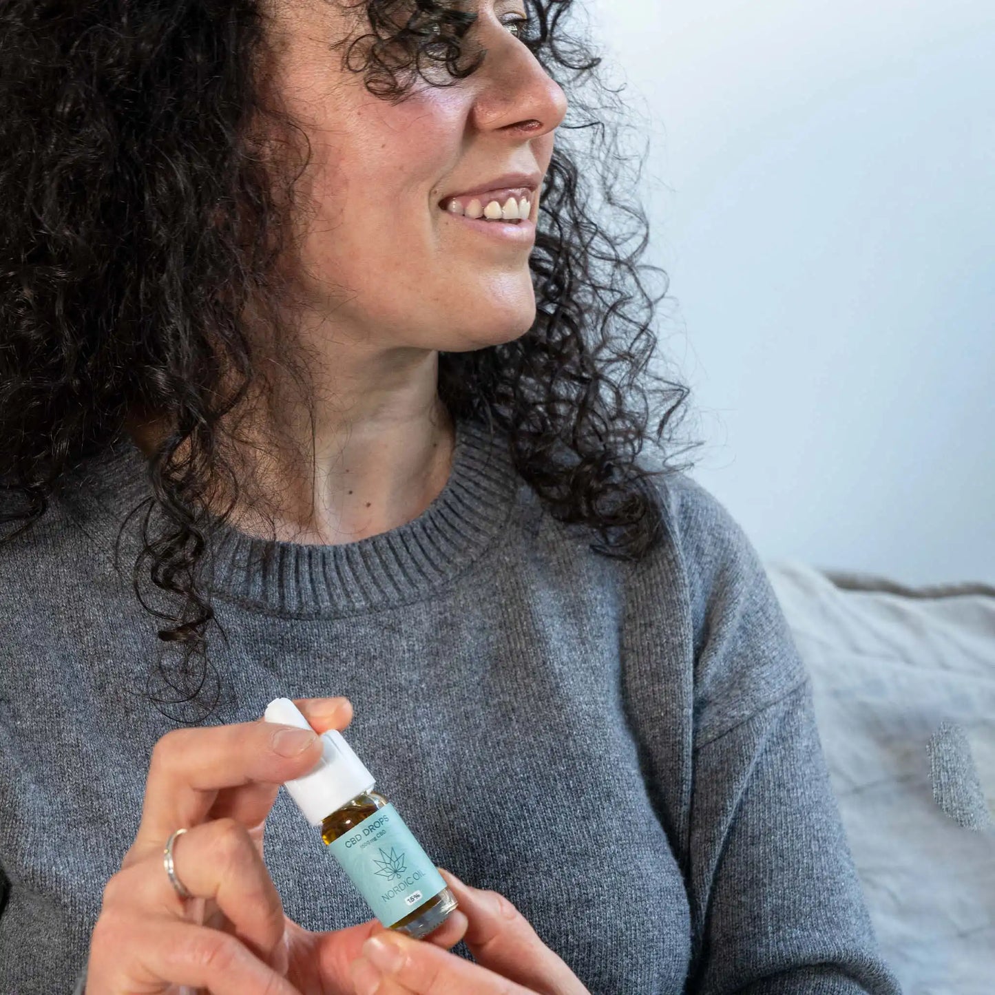 uma mulher sorridente segura o óleo CBD na sua mão
