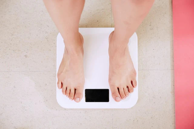 Uma pessoa a verificar o seu peso corporal com uma balança.